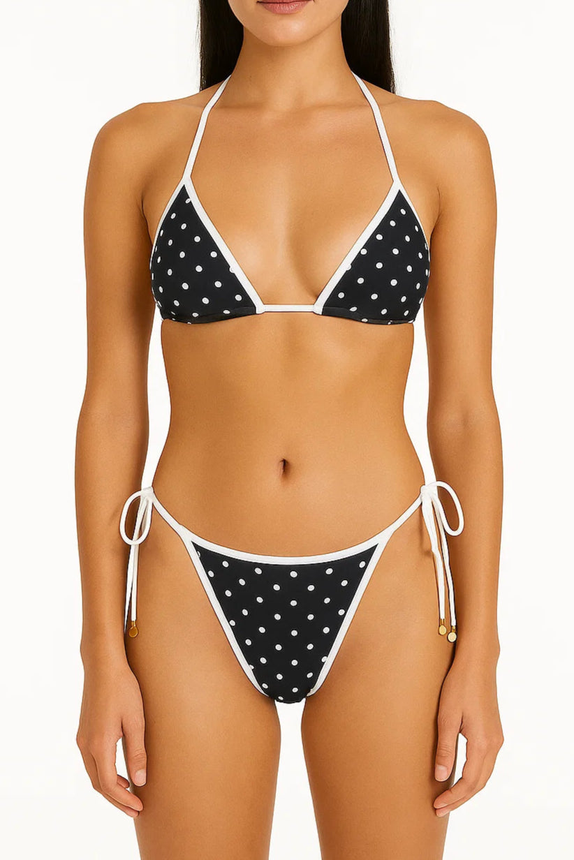 Woman wearing a black and white polka dot bikini on a white background